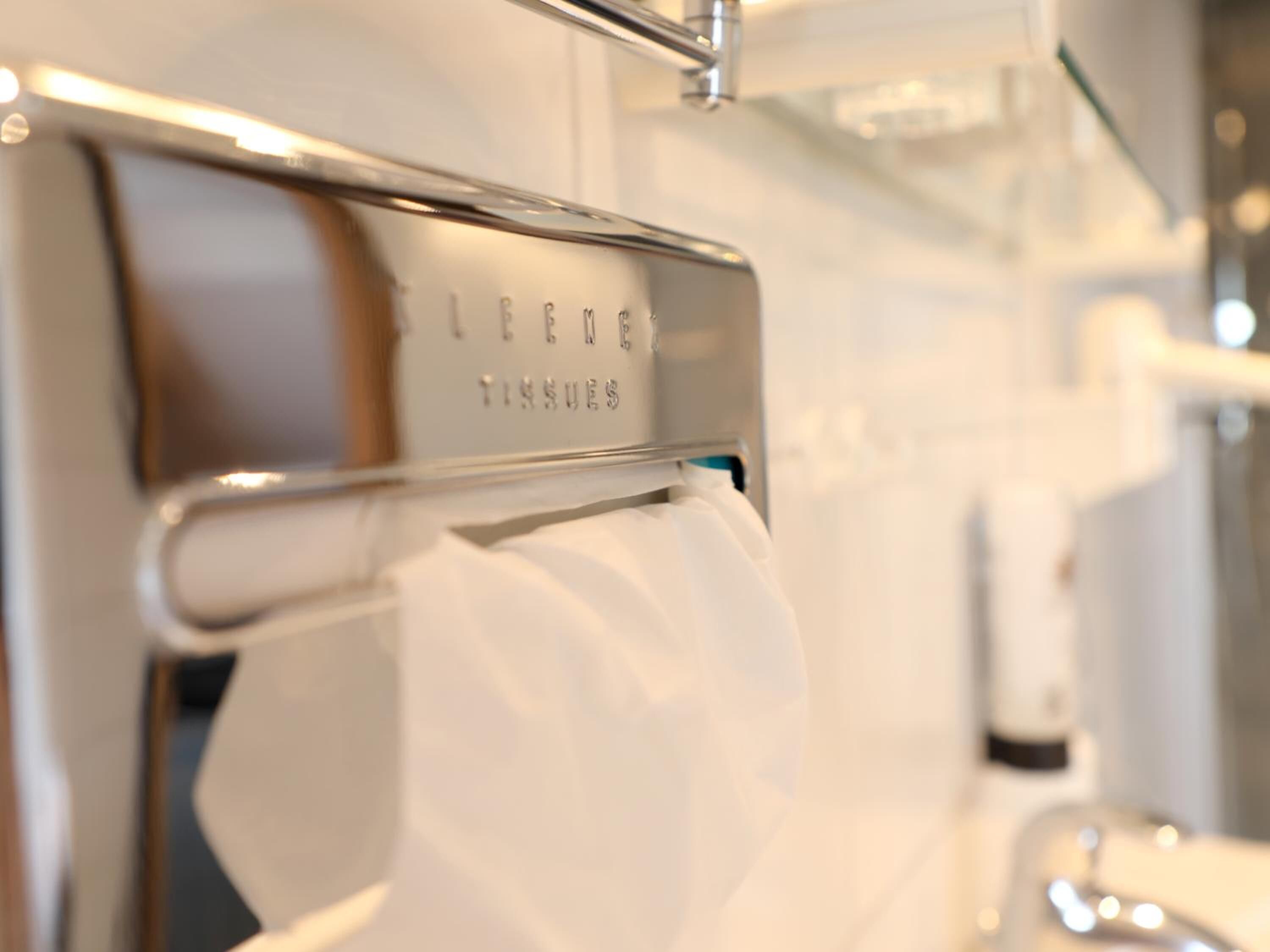 A tissue dispenser in a hotel room with a label that reads "TISSUES".