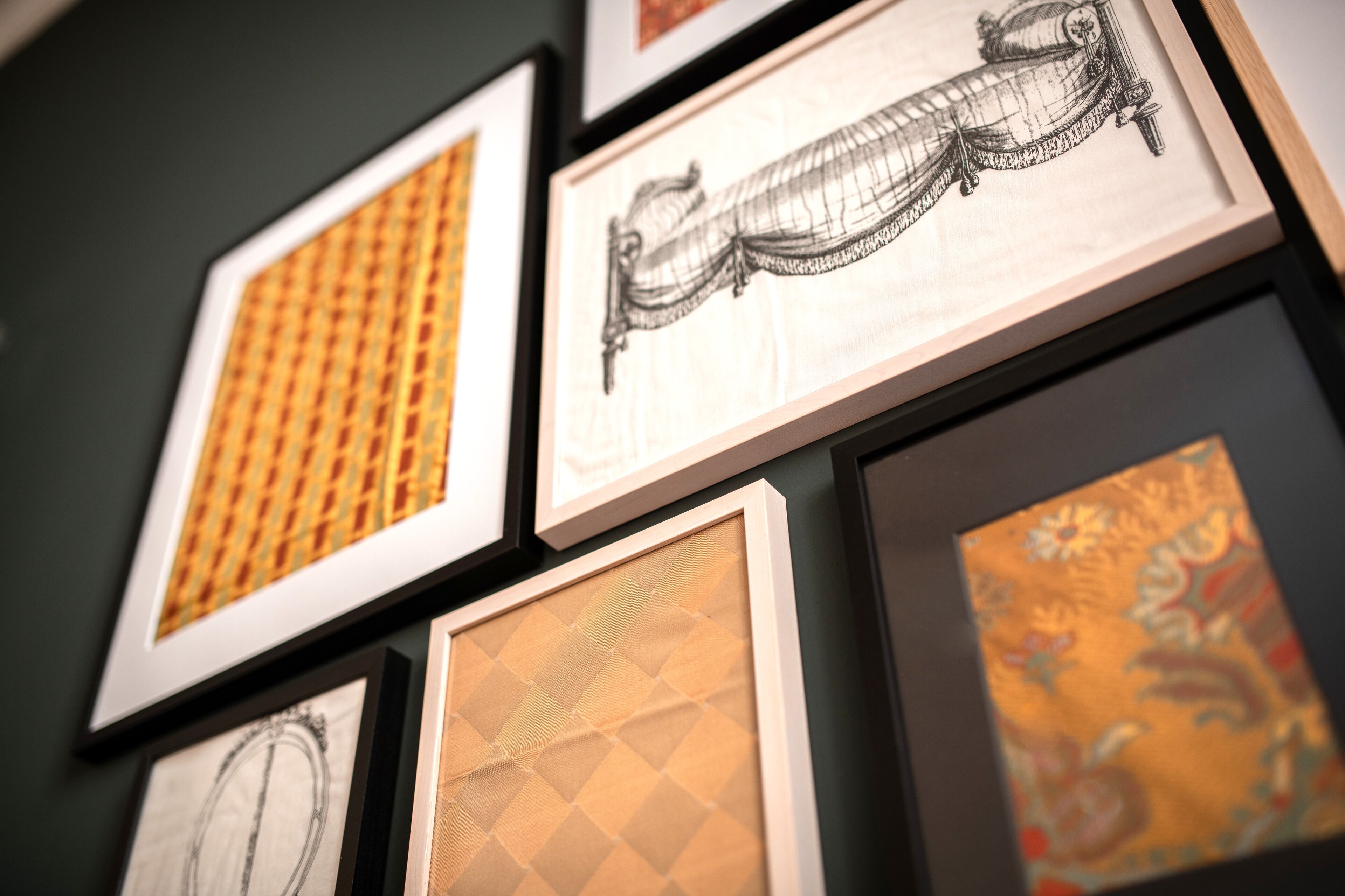 Una pared decorada con cuadros que incluyen patrones geométricos y un dibujo detallado.