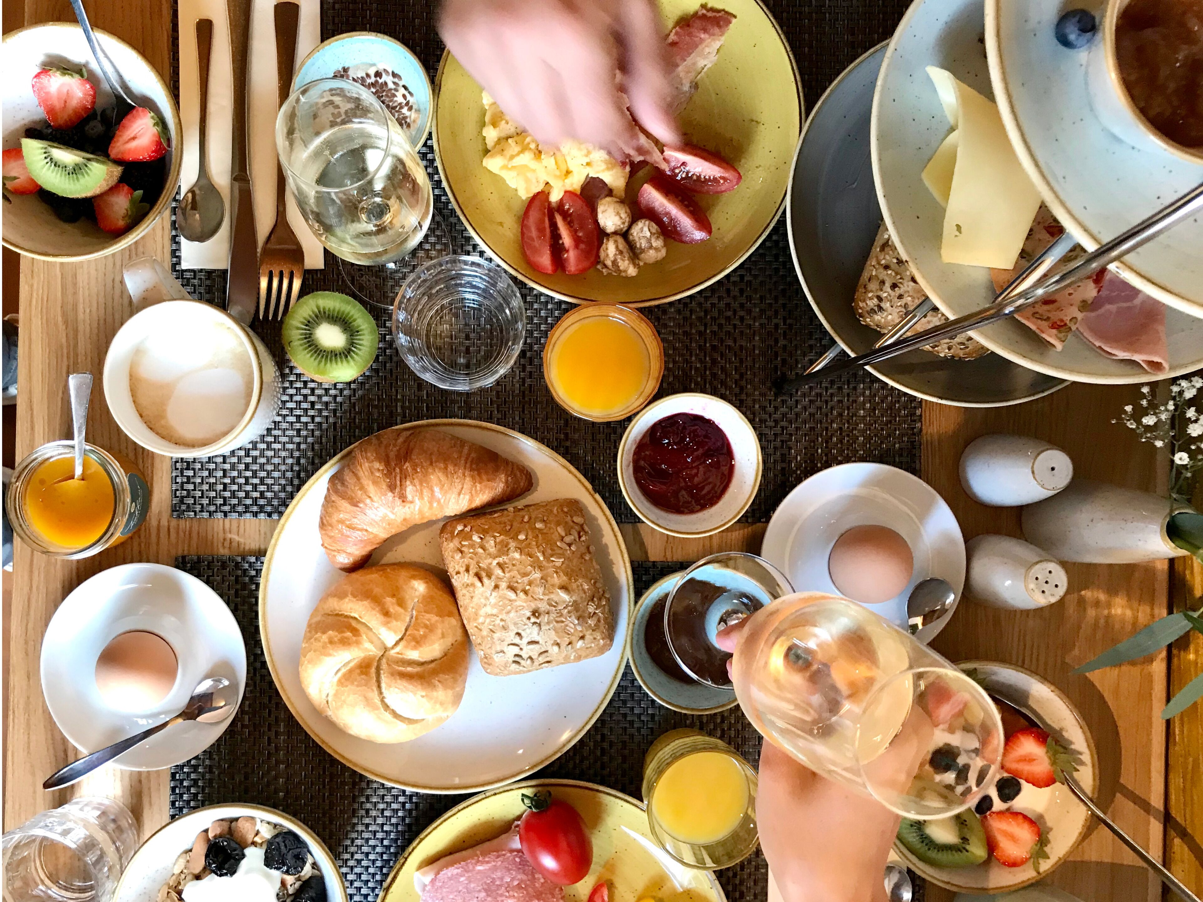 Desayuno con diversas opciones de comida, como tostadas, cruasanes y un bol de fruta.