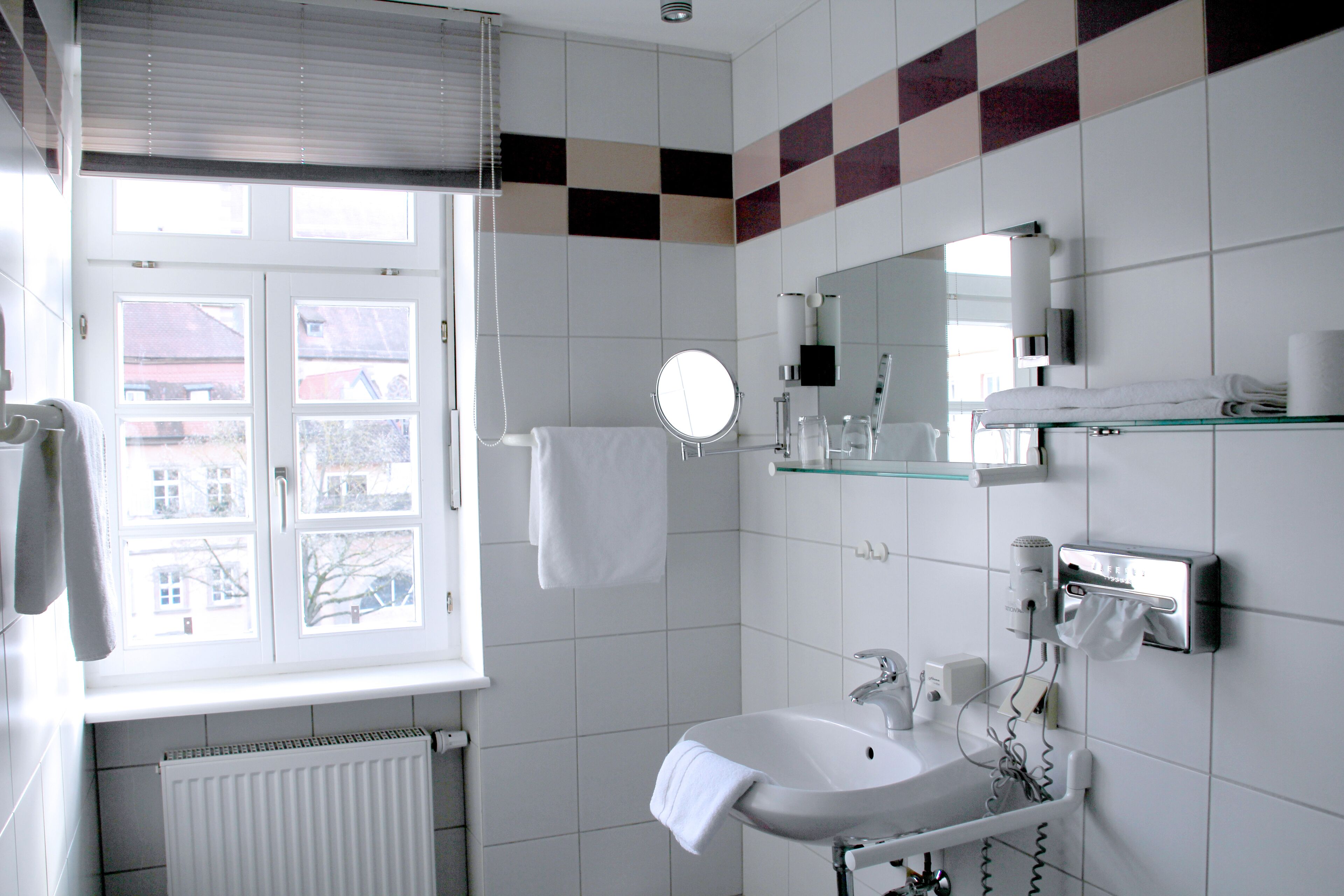 Une salle de bain moderne avec une fenêtre, un lavabo blanc et un miroir.