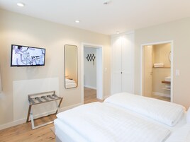 Quarto de hotel com duas camas, televisão, espelho e guarda-roupa.