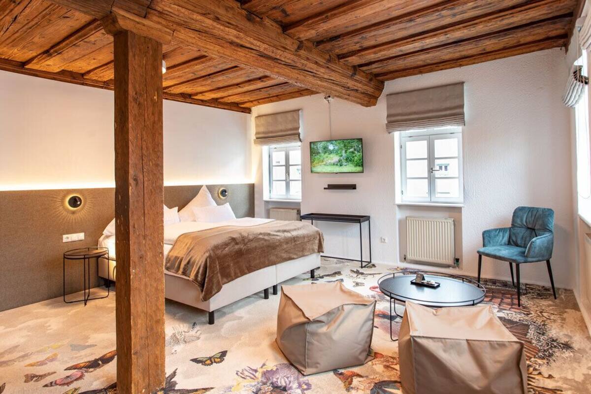 A bedroom with a bed, a television, a chair, and a small table.