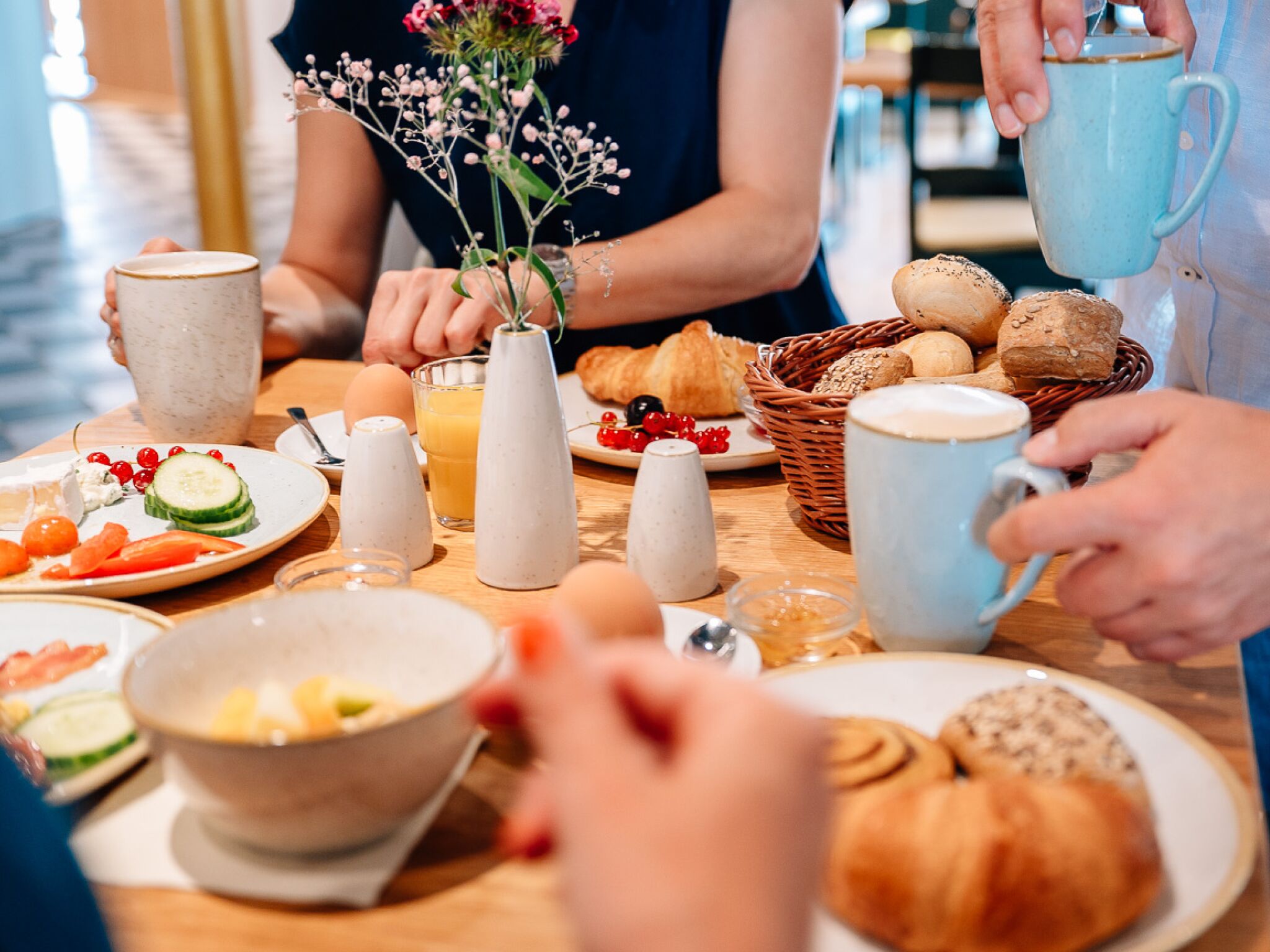 A breakfast setting with various food items, including croissants, eggs, and a bowl of fruit.