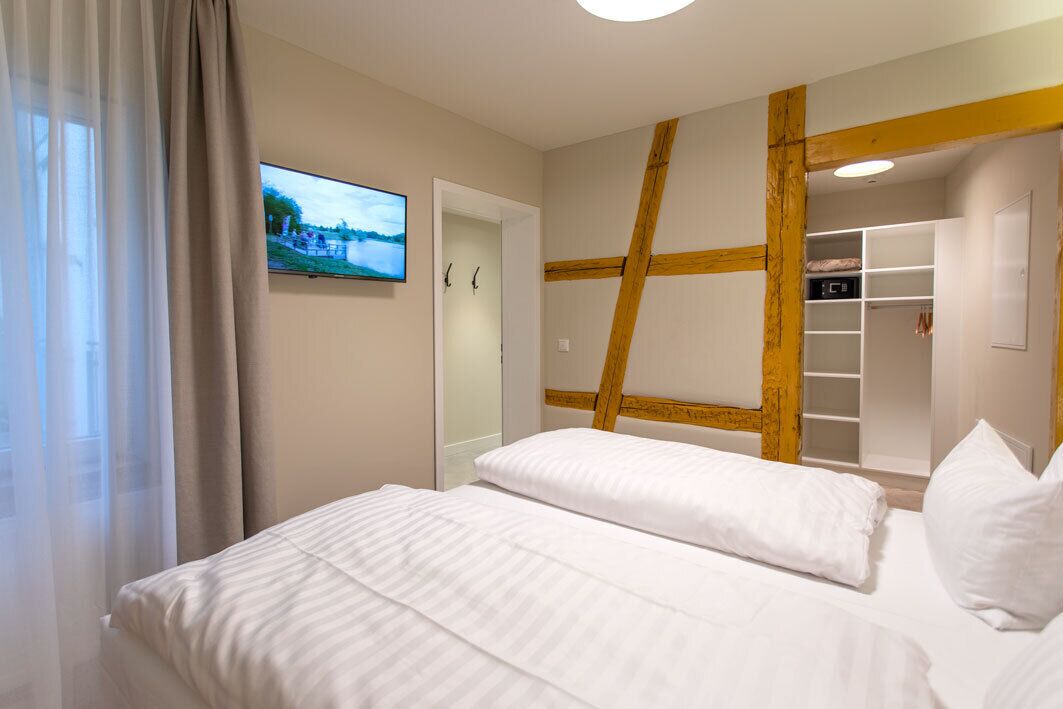Une chambre d’hôtel équipée d’un lit, d’une télévision, d’une armoire et d’un mur décoratif en bois.
