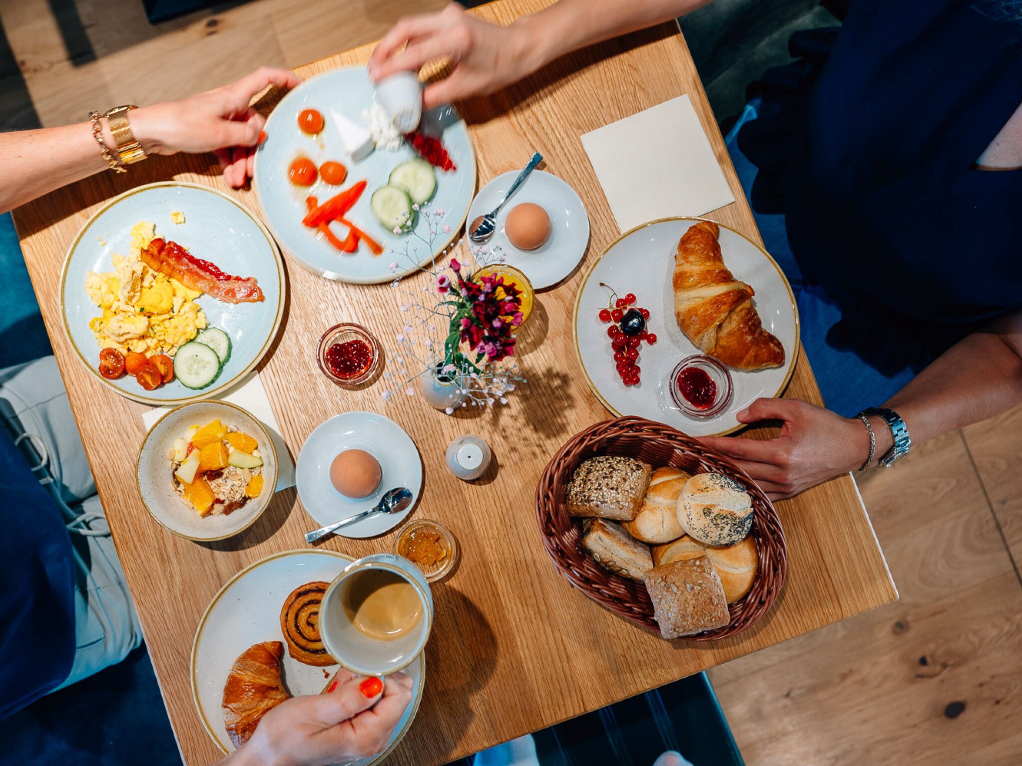 Una mesa con varios alimentos para el desayuno, como huevos, tostadas y bollería.