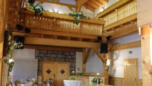 A spacious hall with high wooden ceilings and a stone wall. There are tables set up for dining, and a balcony with a railing. - Landgasthof Scherer (Wenden)