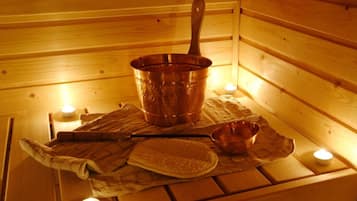A sauna room with a wooden bench, a copper bucket, a wooden spoon, and a small bowl.