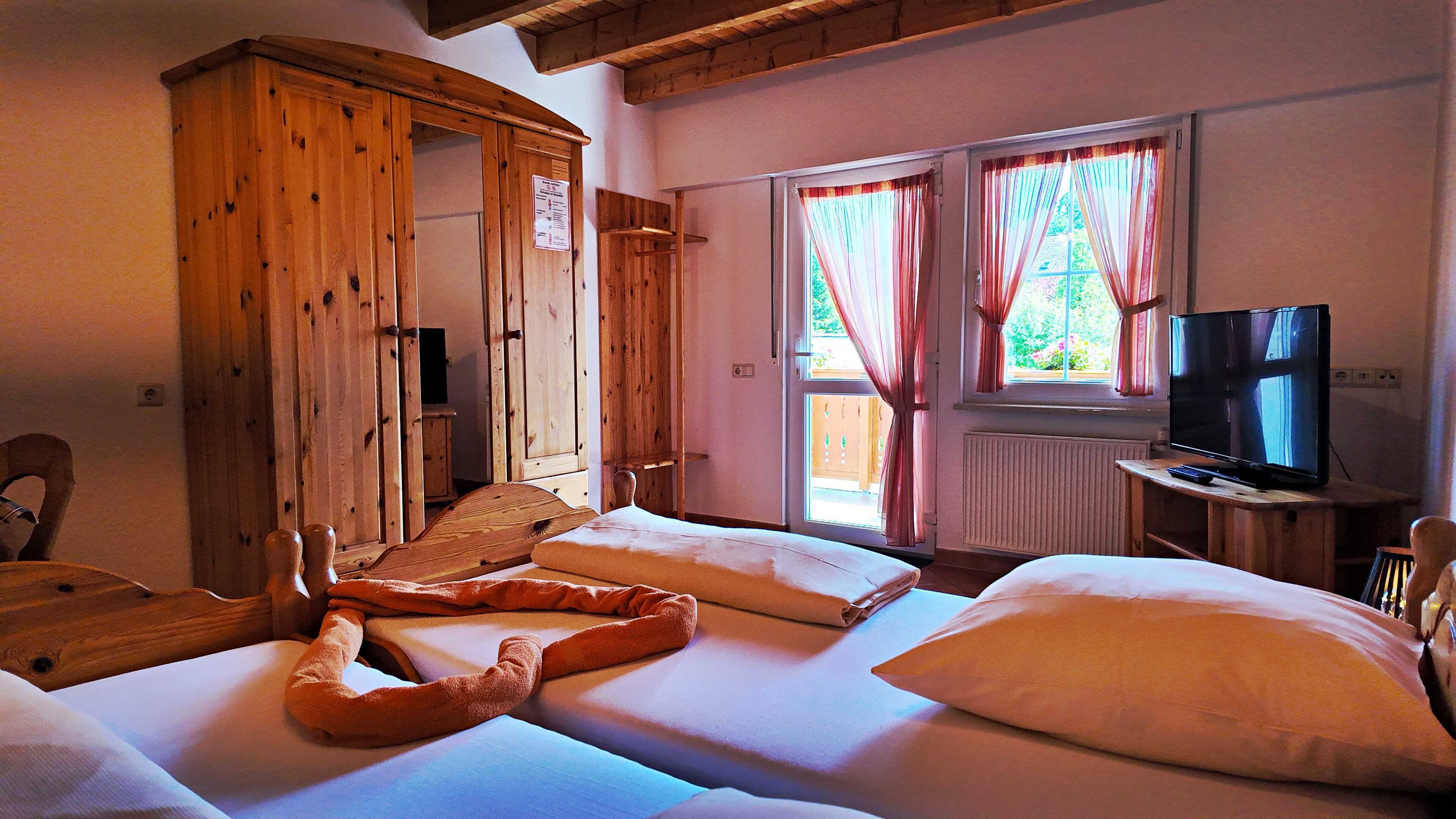 A room with a bed, a television, wooden furniture, and a window with curtains.