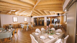 A spacious dining hall with wooden beams on the ceiling, multiple tables set for dining, and a view into another room. - Landgasthof Scherer (Wenden)