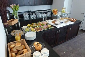 A buffet setup with various food items, glassware, and a vase of flowers. - Hotel und Café Paso (Vierkirchen)