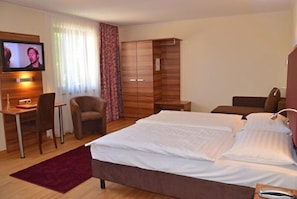 A hotel room with a bed, a desk, a television, a wardrobe, and a chair. - Hotel und Café Paso (Vierkirchen)