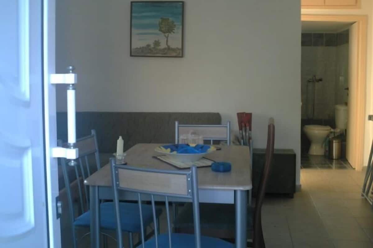 A dining area with a table, chairs, and a painting on the wall.