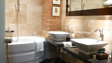 Un baño moderno con bañera, dos lavamanos, un espejo grande y una pared de ladrillo decorativa.