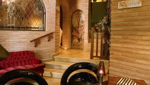 Un área de recepción con pared de ladrillo, un sofá rojo, una escalera y un letrero que dice "Recepción".