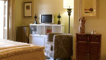 A hotel room with a bed, a chair, a television, a cabinet, and a lamp.