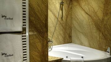 A bathroom with a marble wall, a bathtub, and two towels hanging on a rack.