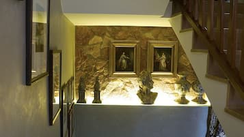 Un escalier avec un mur en pierre et des œuvres d’art encadrées.