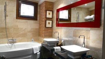 A modern bathroom with a large bathtub, two sinks, and a red-framed mirror.