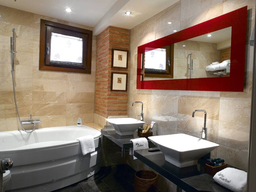 Un baño moderno con una bañera grande, dos lavamanos y un espejo con marco rojo.