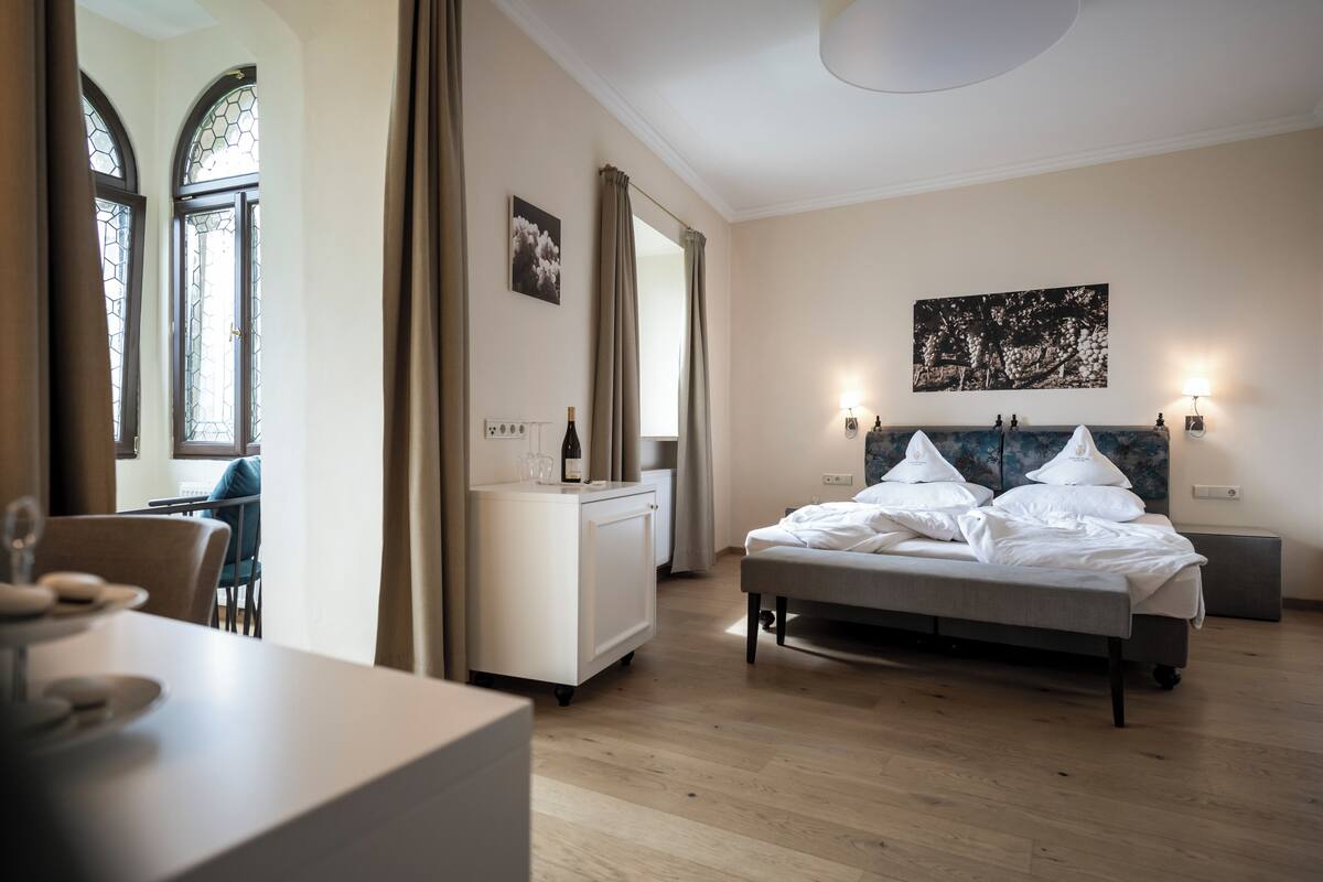 Quarto de hotel com cama, mesa de cabeceira e escrivaninha com cadeira.