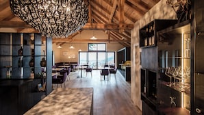 Un amplio bar con vigas de madera, una lámpara colgante grande y vistas al exterior.