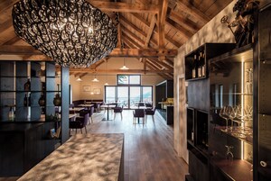 Un amplio bar con vigas de madera, una lámpara colgante grande y vistas al exterior.