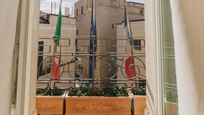 A balcony with a view of a bell tower and flags. - Hotel San Nicola (Altamura)
