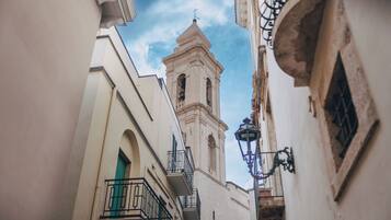 Una calle estrecha con un alto campanario y un farol.