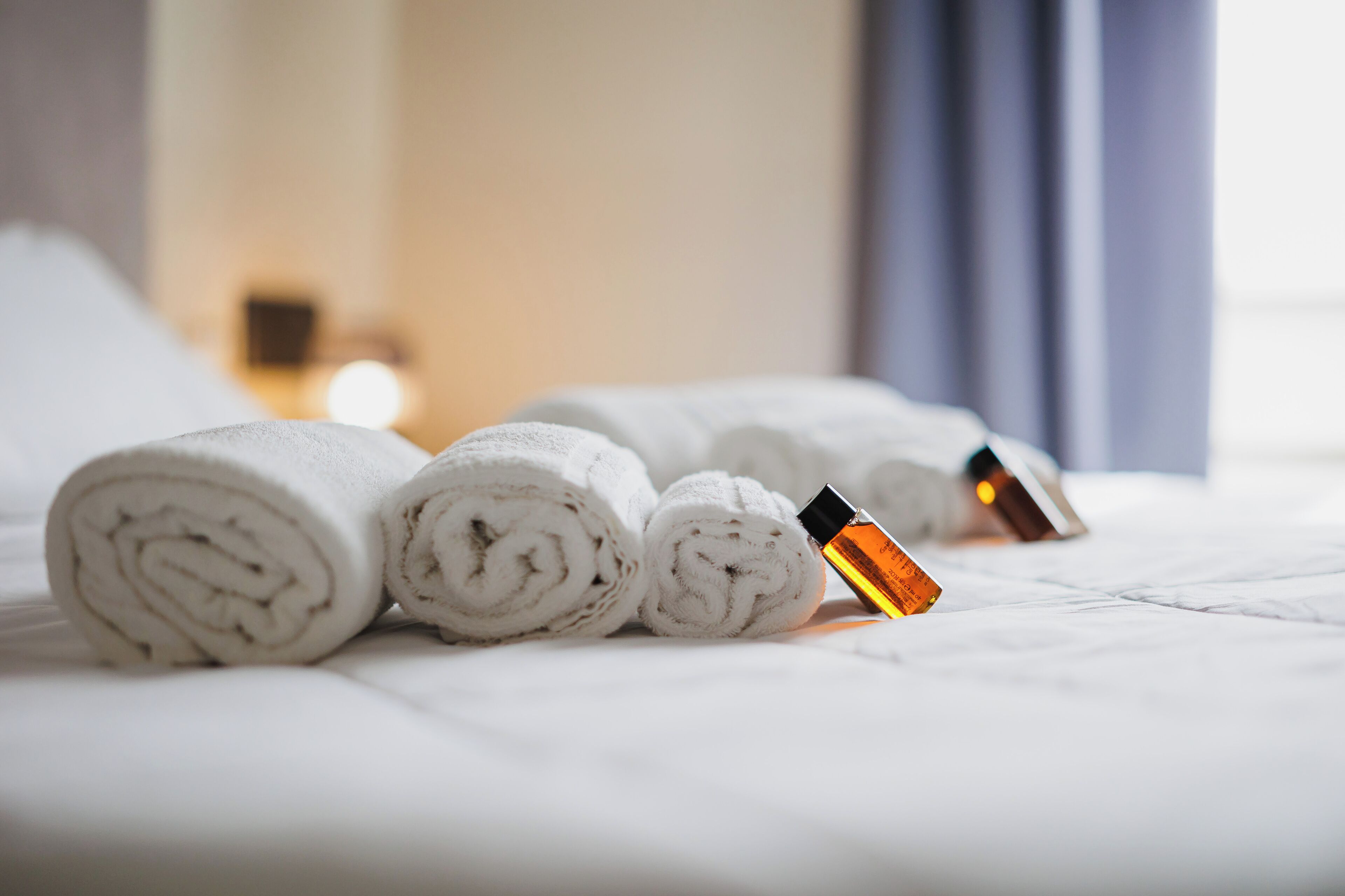 Un lit bien fait, avec des serviettes blanches roulées et une bouteille de lotion.