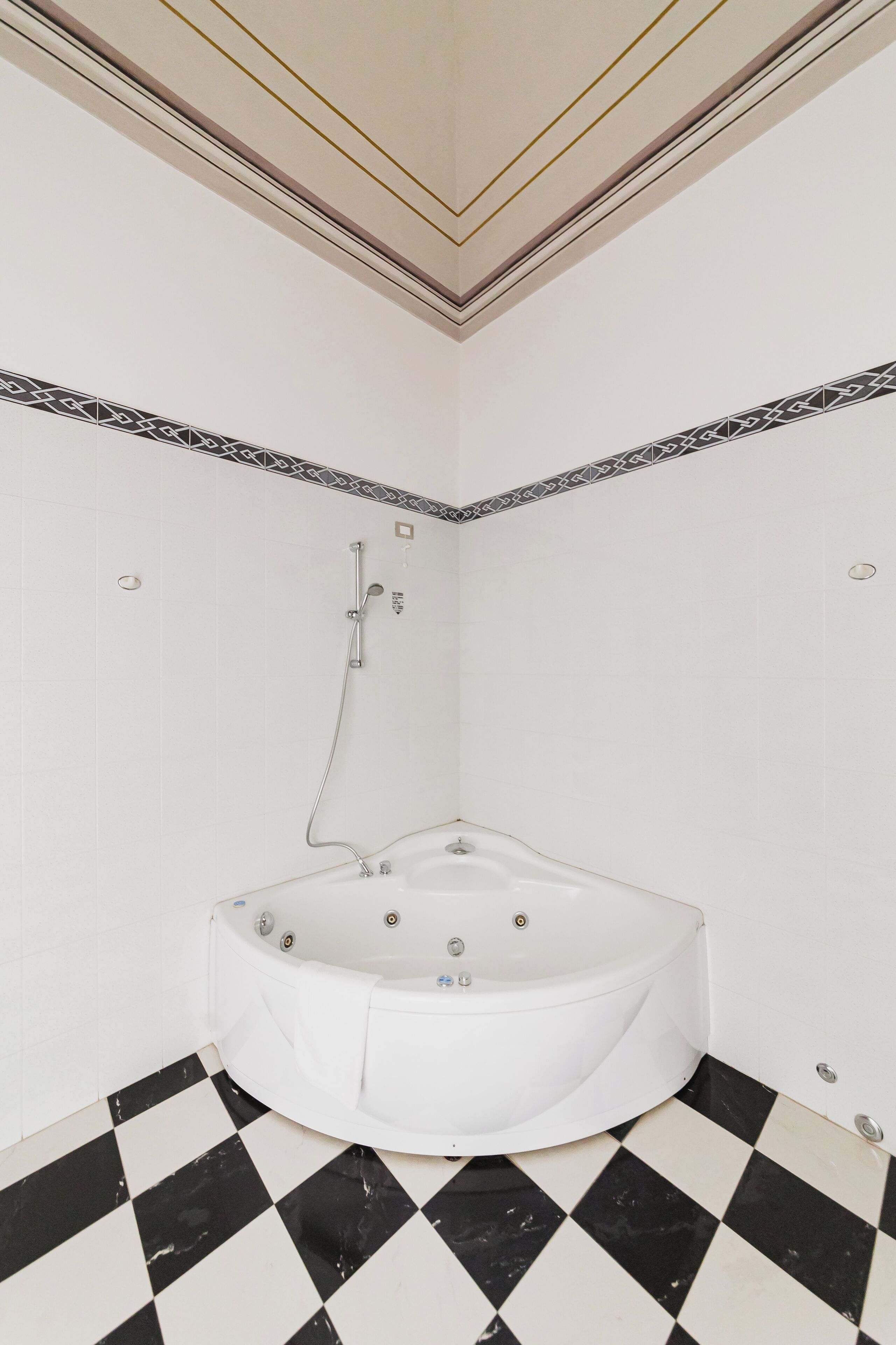 A bathroom with a white bathtub, black and white checkered floor, and patterned wall tiles.