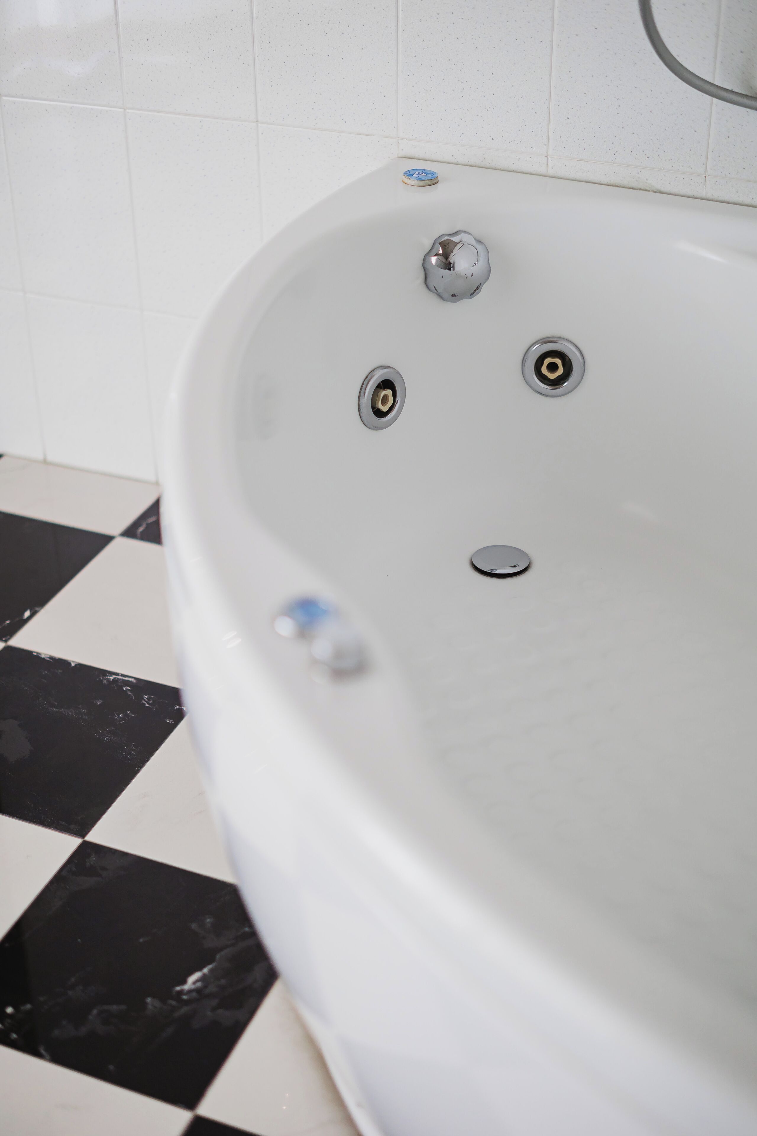 A white bathtub with three faucets and a drain.
