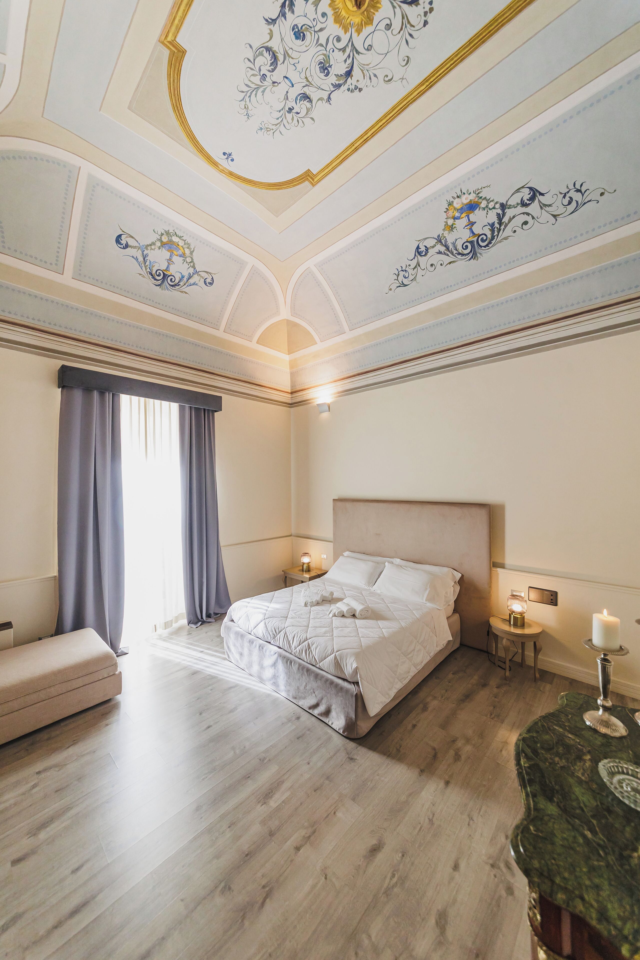 Une chambre à coucher avec un grand lit, une table de chevet, une lampe et un plafond décoratif.