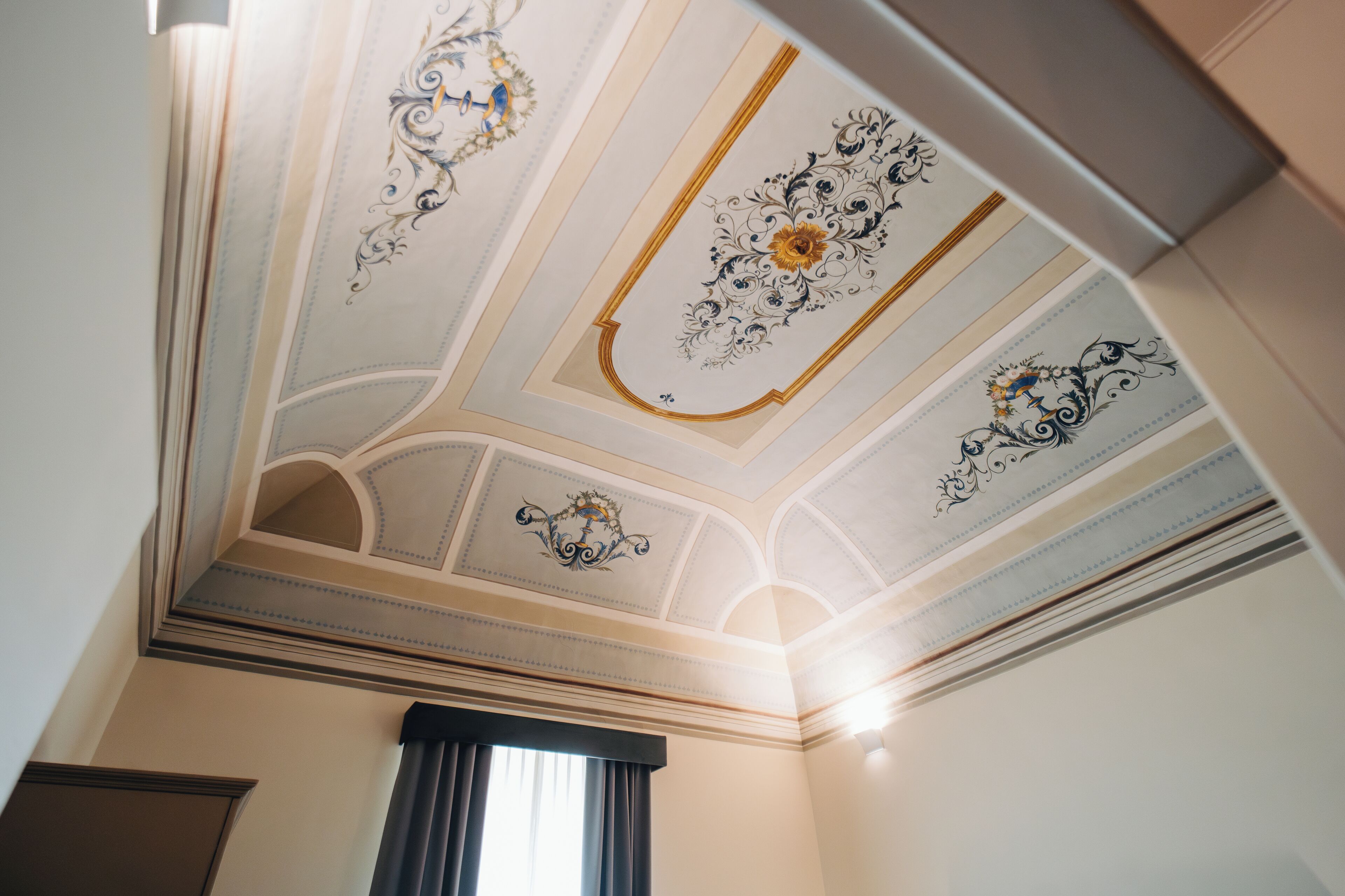 A room with a decorative ceiling featuring ornate designs and a central floral motif.