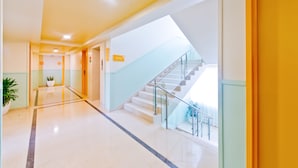 A modern hotel lobby with a marble floor, a staircase, and a potted plant. - Bloom Hotel - Indiranagar  (Bengaluru)