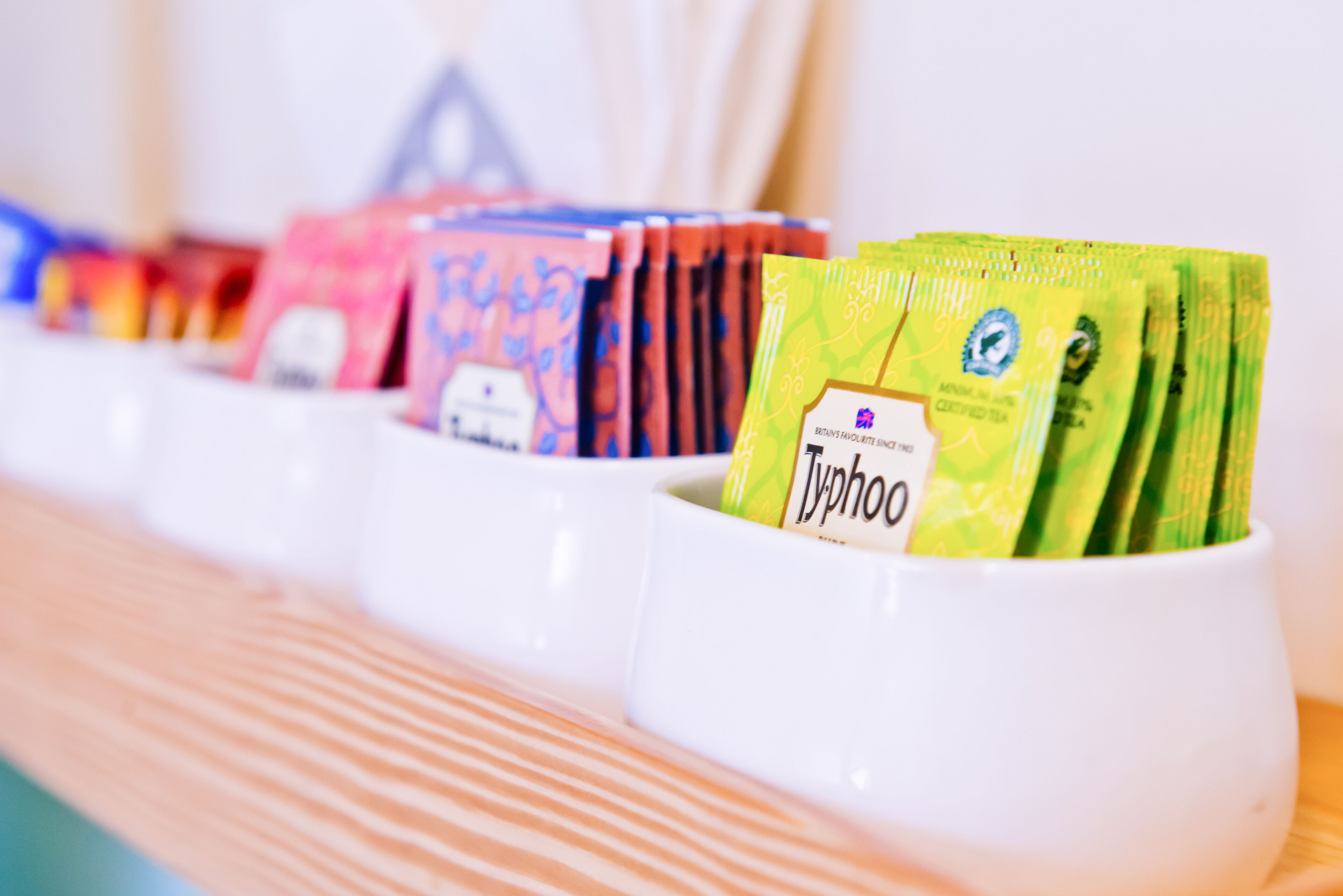 A row of white cups containing different tea bags.