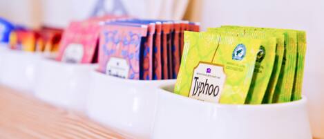 A row of white cups containing different tea bags.