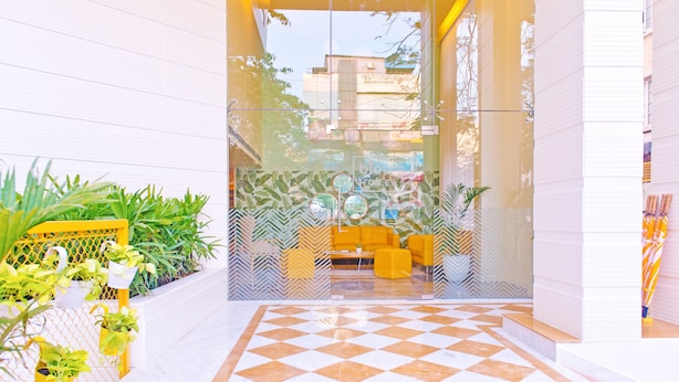 A lobby with a checkered floor, yellow seating, and potted plants. - Bloom Hotel - Indiranagar  (Bengaluru)