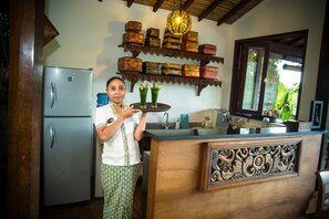 Uma cozinha com geladeira, bancada de madeira e prateleira com caixas decorativas.