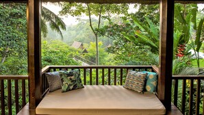 A wooden deck with a mattress and pillows, surrounded by lush greenery and a view of a forested area. - Amori Villas (Ubud)