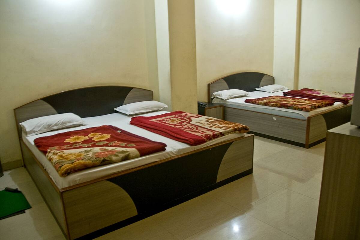 A hotel room with two beds, each with a headboard and a red floral bedspread.