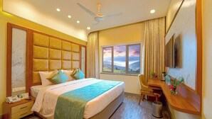 Habitación de hotel con una cama grande, un escritorio, una silla, un teléfono y una ventana con vistas a las montañas.