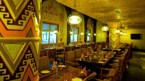 Un restaurante con mesas y sillas de madera, decorado con motivos geométricos en las paredes.