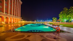 Una piscina con diseño de tiburón, rodeada por un edificio de columnas bajo un cielo nocturno.