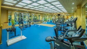 Un gimnasio con equipos de ejercicio variados, piso azul y una amplia pared de espejos.