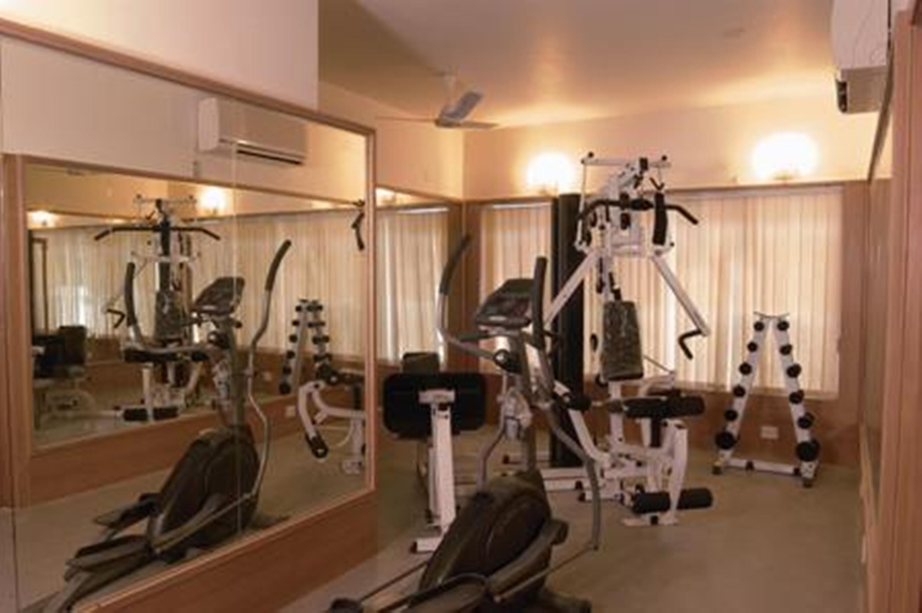 A gym with exercise equipment, a large mirror, and a ceiling fan.