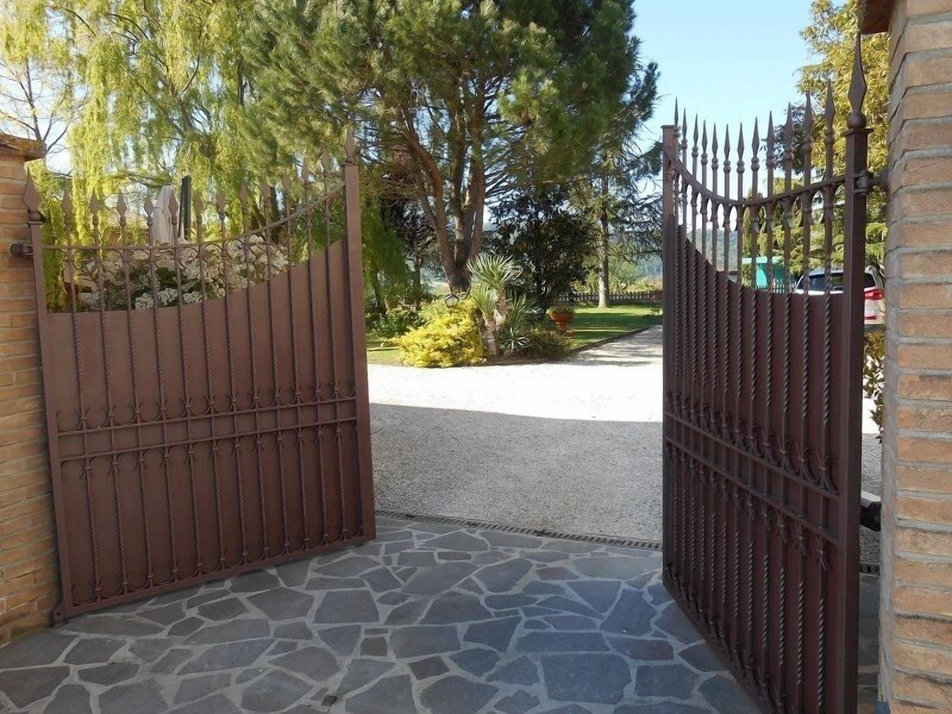 Une entrée fermée par un portail, avec un chemin de pierre menant à une allée.