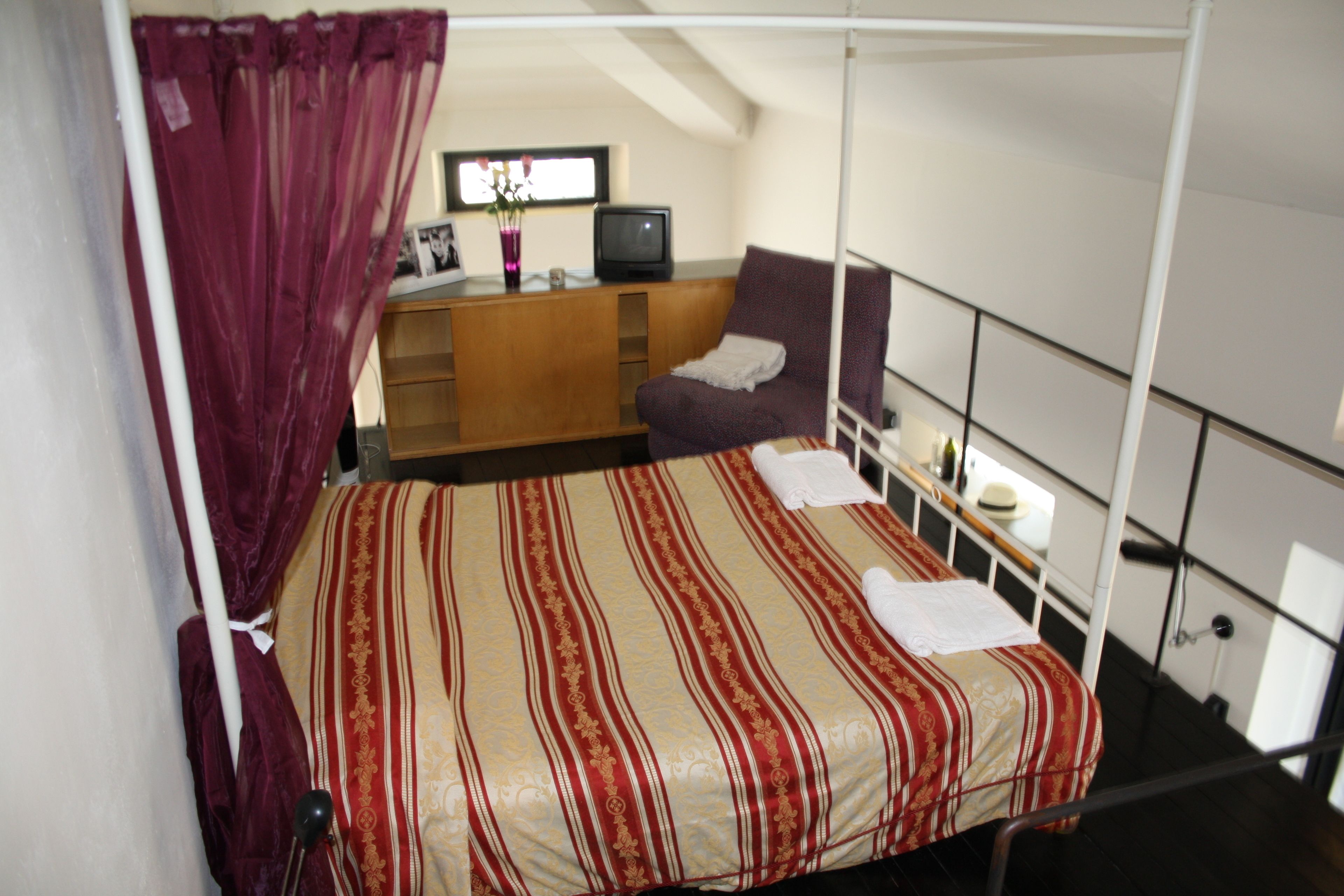 Una camera da letto con un letto, una scrivania, una sedia e un televisore.