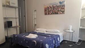 A hotel room with a bed, a small bedside table, a shelf unit, and a painting on the wall. - Romeo and Juliet B&B and Apartaments (Bergamo)