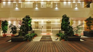 Eine moderne Lobby mit Holzboden, Topfpflanzen und einem zentralen Aufzug.