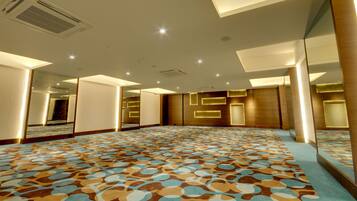 Una habitación amplia con alfombra estampada, paredes espejadas e iluminación empotrada.